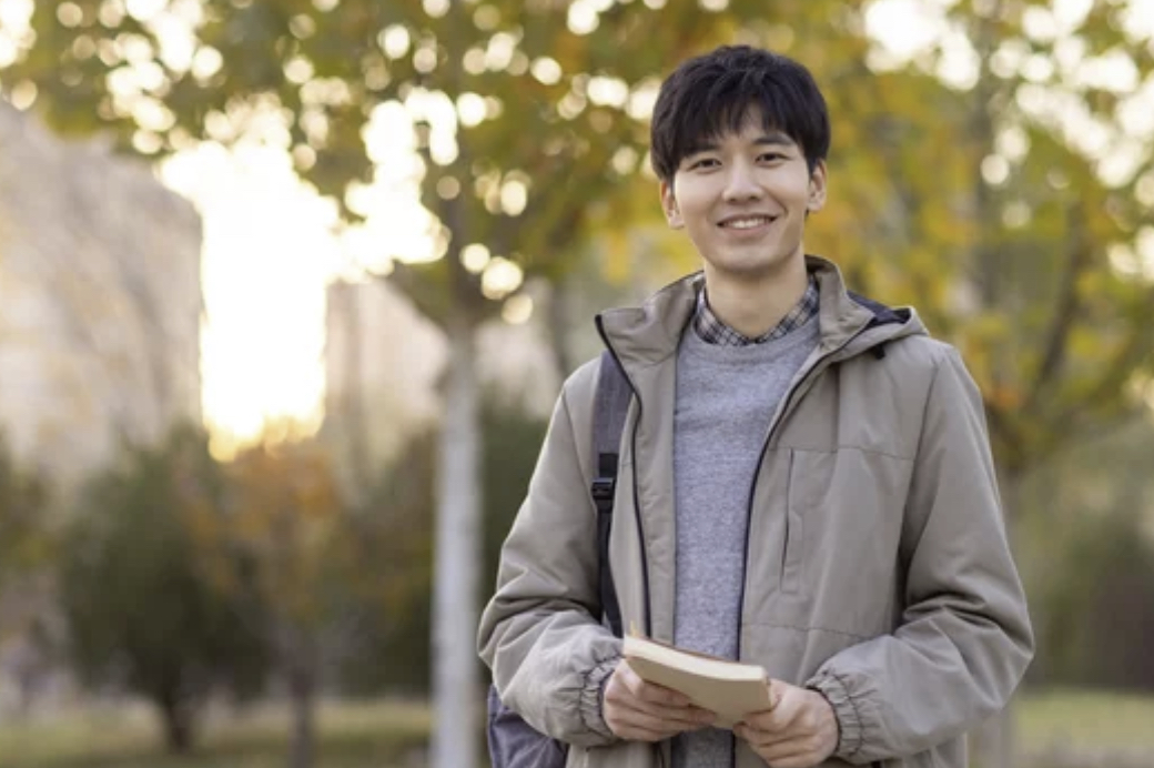 A student holding a book outdoors